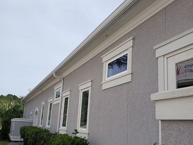Seamless gutters installed along the roofline of a stucco building Seamless gutters installed along the roofline of a stucco building