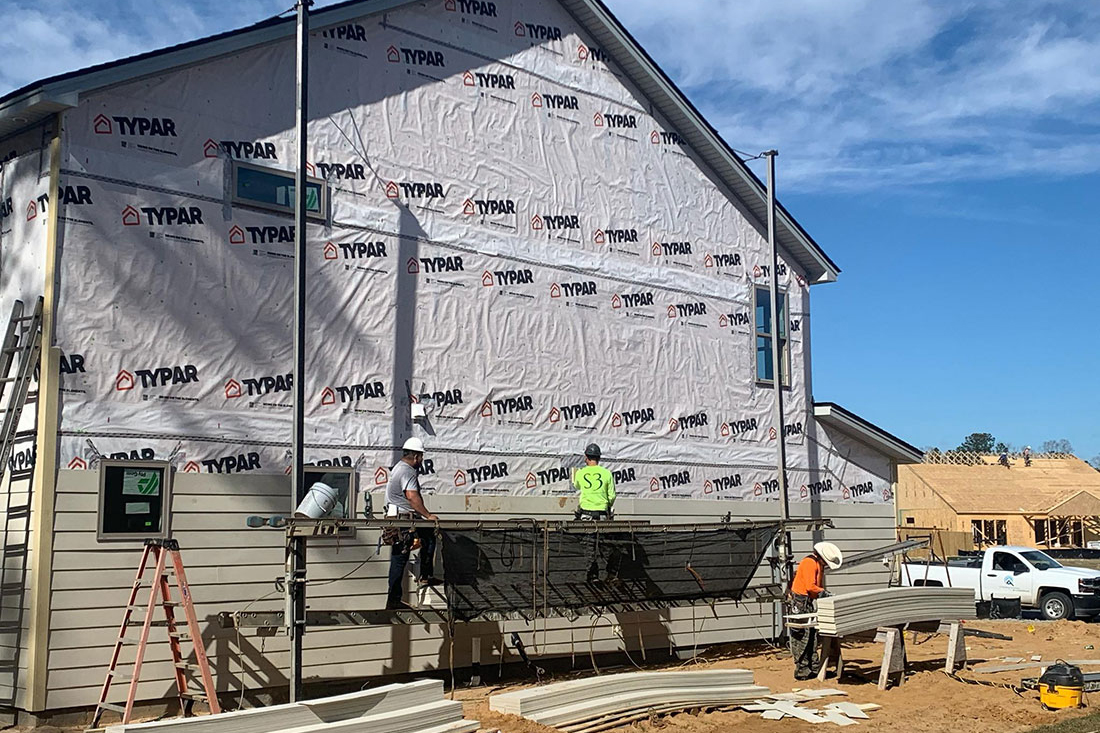 Construction workers installing siding over house wrap on a new home Construction workers installing siding over house wrap on a new home